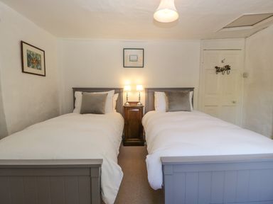 A bedroom with two single beds and a nightstand with lamps at Small Piece in Porlock