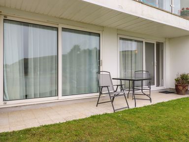 A patio with two chairs and a table outside sliding glass doors at 7 Europa Court in Mawgan Porth