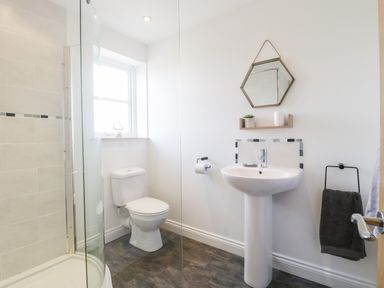 A bathroom with a toilet sink shower and a hexagonal mirror at The Coal House at Mendip View in Wedmore