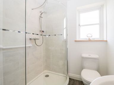 A bathroom with a corner shower enclosure a toilet and a window at The Coal House at Mendip View in Wedmore