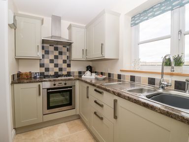 A kitchen with built in oven gas stove sink and window with fish patterned blind at The Coal House at Mendip View in Wedmore