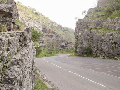 A winding road passing between rocky cliffs with a parking area at The Coal House at Mendip View in Wedmore