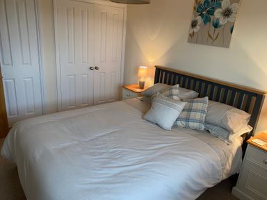 A bedroom with a made bed two nightstands with lamps and double-door closet at The Coal House at Mendip View in Wedmore