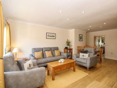 A living room with gray sofas wooden coffee table and dining table at Inglewood in Keswick