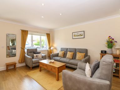 A living room with grey sofas yellow cushions wooden coffee table and a window with yellow curtains at Inglewood in Keswick
