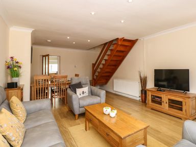A living room with grey sofas wooden coffee table television and wooden staircase at Inglewood in Keswick