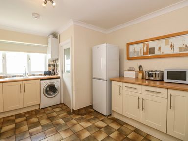 A kitchen with a washing machine fridge microwave toaster and cabinets at Inglewood in Keswick