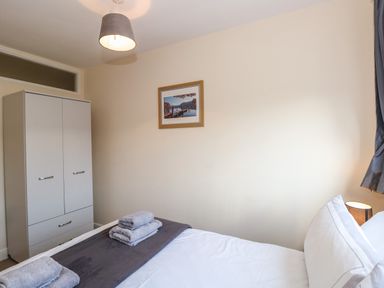 A bedroom with a bed with folded towels a wardrobe a lamp a framed picture on the wall at Inglewood in Keswick