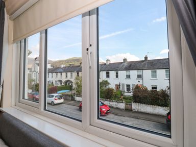 View through a window of a residential street with parked cars and rows of houses at Inglewood in Keswick
