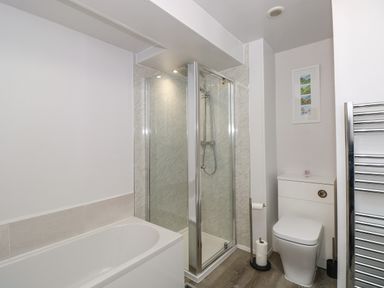 A bathroom with a bathtub shower unit toilet and a towel rack at Inglewood in Keswick