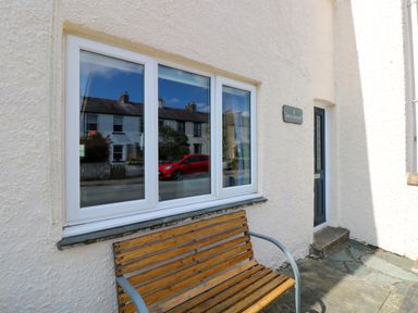 A wooden bench outside a house with a window and a door with a nameplate Inglewood in Keswick