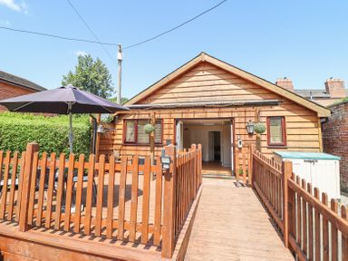 A wooden deck with a table and umbrella in front of a wooden house at Varley Villa in Newtown