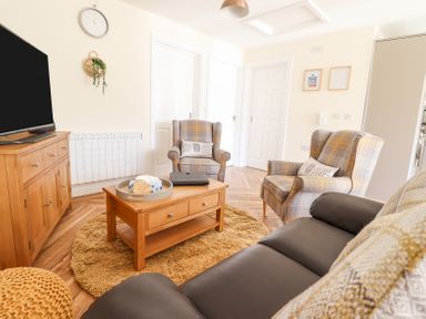A living room with two armchairs a sofa wooden coffee table and television at Varley Villa in Newtown