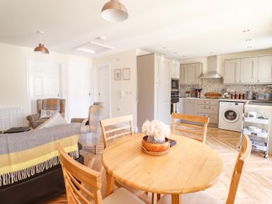 A kitchen and dining area with a round wooden table and chairs and a washing machine at Varley Villa in Newtown