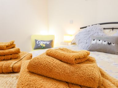 Stacked orange towels on a bed with cushions and a lamp in a bedroom at Varley Villa in Newtown