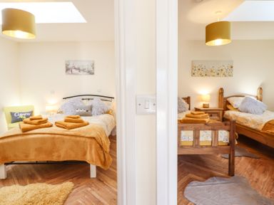 Two bedrooms separated by a wall each with beds, bedside tables, lamps, and towels on the beds at Varley Villa in Newtown