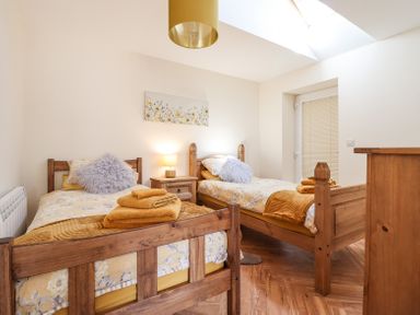 A bedroom with two single wooden beds bedside table with a lamp and folded towels on the beds at Varley Villa in Newtown