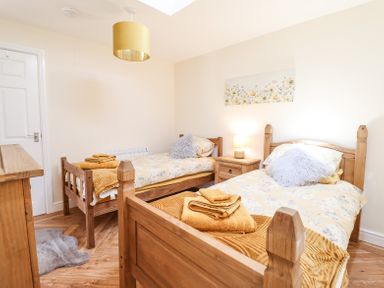 A bedroom with two wooden single beds a nightstand with lamp and folded towels at Varley Villa in Newtown
