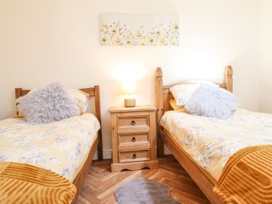 A bedroom with two single beds and a wooden nightstand with a lamp at Varley Villa in Newtown