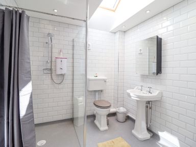 A bathroom with a shower area a toilet a sink a mirror and skylight at Varley Villa in Newtown