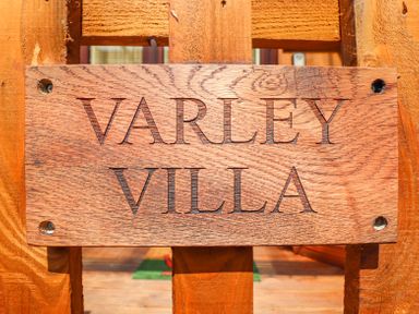 A wooden sign with the text Varley Villa mounted on a wooden gate at Varley Villa in Newtown