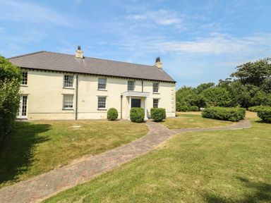 A house with a garden pathway and bushes at Clynnog House in Dwyran near Newborough