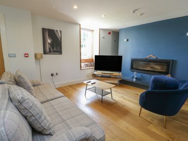 A living room with a sofa, coffee table, and television at Clynnog House in Dwyran near Newborough