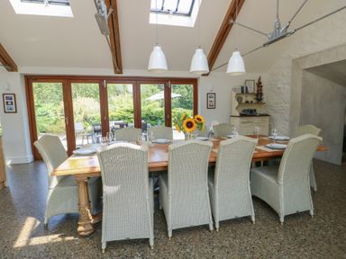 A dining room with a large table and sliding doors at Clynnog House in Dwyran near Newborough