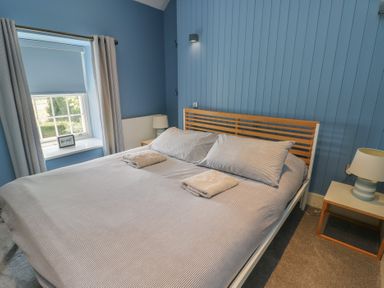 A bedroom with a bed and window at Clynnog House in Dwyran near Newborough