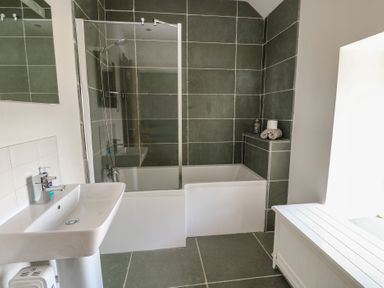A bathroom with a bathtub and shower at Clynnog House in Dwyran near Newborough