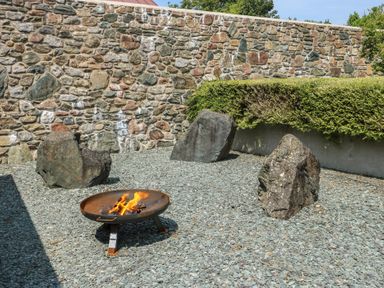 An outdoor space with a fire pit and stones at Clynnog House in Dwyran near Newborough