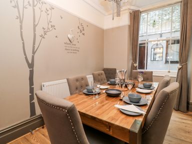 A dining room with wooden table set for six and gray upholstered chairs at Albany in Looe