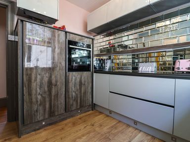 A kitchen with wooden and white cabinets a built in oven a toaster and a microwave on the counter at Albany in Looe