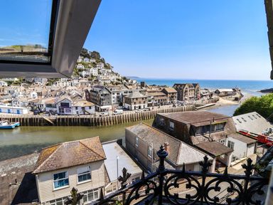 A coastal town with houses along a river and the sea visible in the background at Albany in Looe