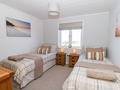A bedroom with two single beds side by side and wooden bedside tables at McAuliffe Lodge in Borth