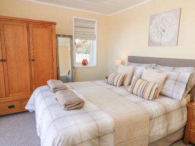 A bedroom with a double bed pillows bedside tables wardrobe and a mirror at McAuliffe Lodge in Borth