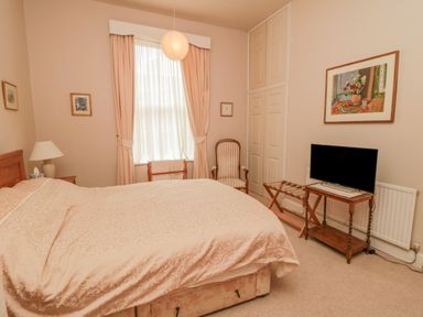 A bedroom with a bed lamp chair TV and a painting at Sandsend Sunset View Whitby