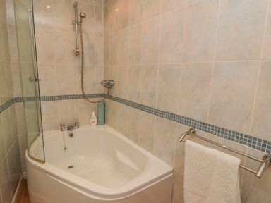 A bathroom with a corner bathtub shower and towel rack at Sandsend Sunset View in Whitby