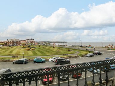 A view of a grassy park area with pathways and parked cars along a road by the sea at Sandsend Sunset View Whitby