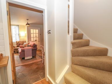 A carpeted staircase next to a living room with a sofa and an armchair at Chapel Cottage in Corbridge