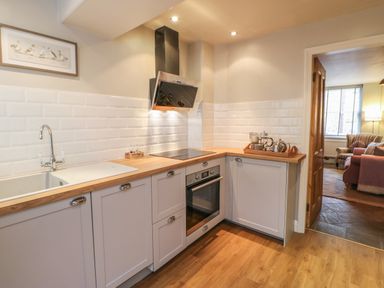 A kitchen with wooden countertops white cabinets a sink an electric stove and an oven at Chapel Cottage in Corbridge