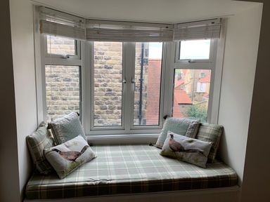 A window seat with patterned cushions and pillows in a room at A Stone's Throw in Alnmouth