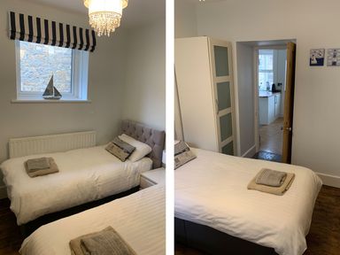 A bedroom with two single beds a window with striped blind and a wardrobe at A Stone's Throw in Alnmouth
