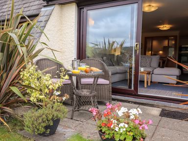 A patio with wicker chairs and a table with juice and croissants outside a living room at Pavey Ark in Ambleside