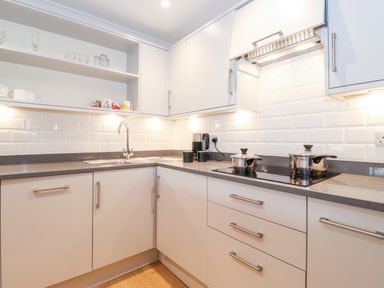 A kitchen with white cabinets countertop and two stainless steel pots on a stove at Pavey Ark Ambleside