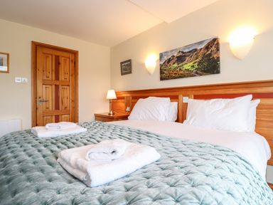 A bedroom with a double bed white towels a wooden door and wall art at Pavey Ark in Ambleside