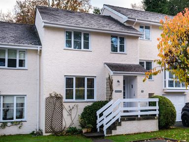The exterior of a two story house with white walls windows stairs and a small front porch with railings at The Neon Rose in Bowness-On-Windermere