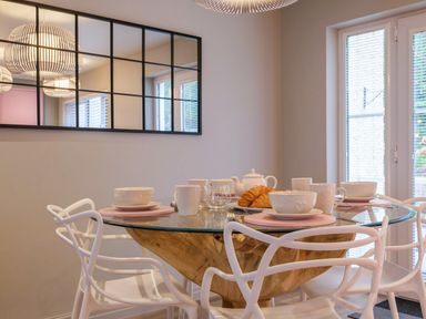A dining area with a round glass table set for breakfast with cups bowls and croissants at The Neon Rose in Bowness-On-Windermere