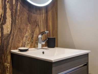 A bathroom sink with a chrome faucet and soap dish against a wood-patterned wall at The Neon Rose in Bowness-On-Windermere