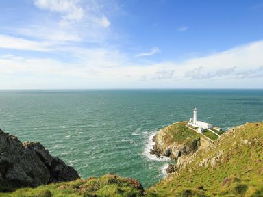 A lighthouse on a rocky coastline overlooking the sea at Glasfryn in Holyhead